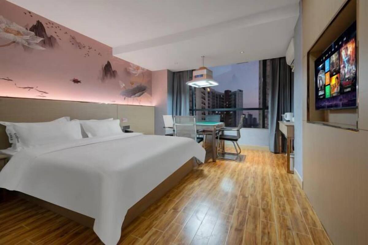 Hotellihuone, jossa on sänky, työpöytä, tuoli, televisio ja näkymä kaupunkiin.