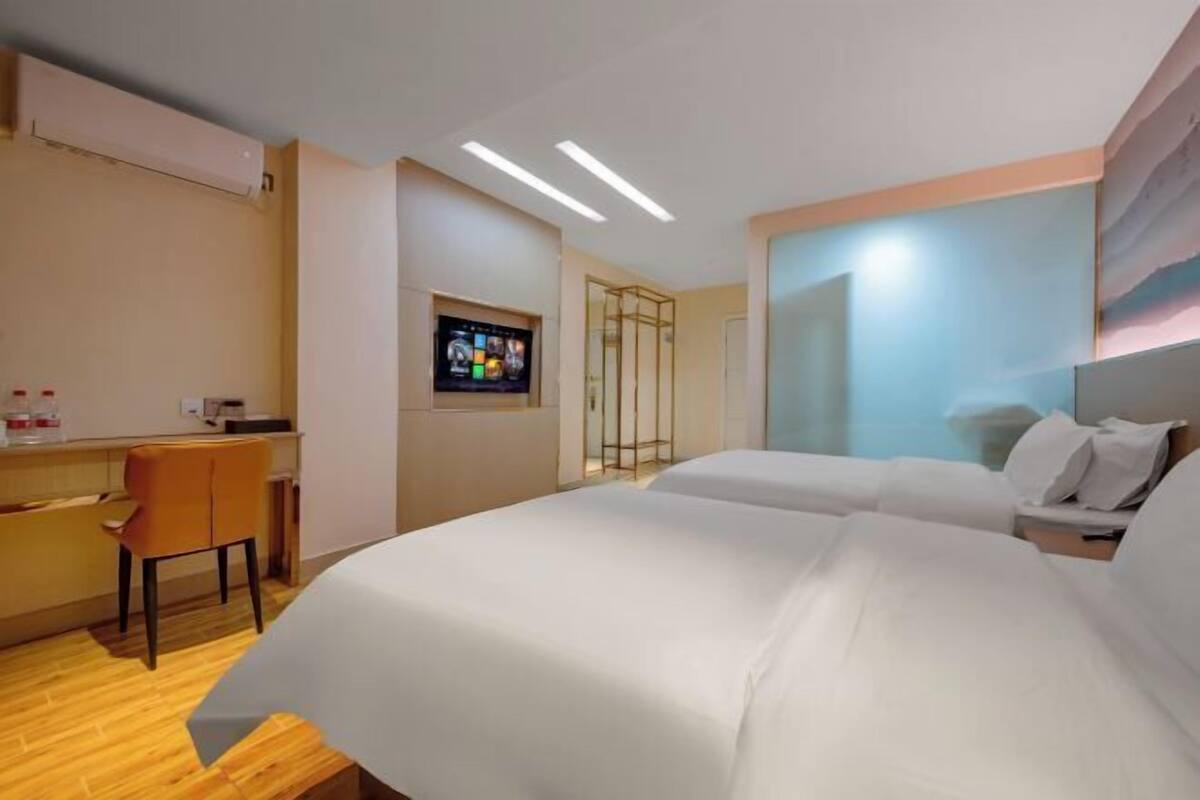Hotellihuone, jossa on sänky, työpöytä, tuoli, televisio ja ovi.