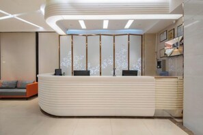 A reception desk with a modern design, a seating area with a sofa, and a decorative wall with patterns. - Aishang Hotel (Da Lang RT Mart) (Dongguan)