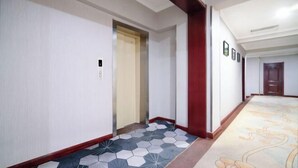 Un pasillo con suelo estampado, una puerta y un interruptor de luz en la pared.