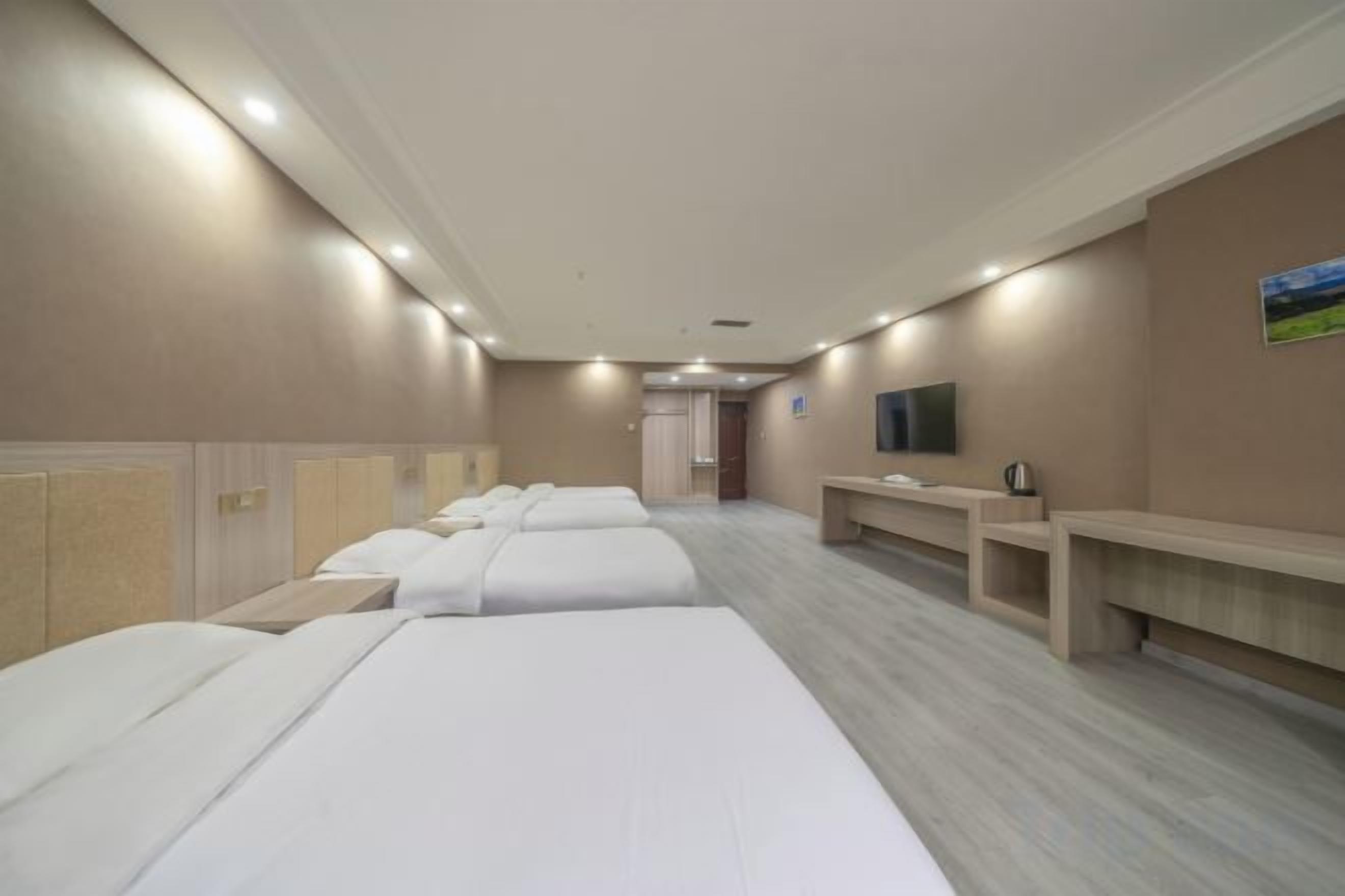 Une chambre d’hôtel avec plusieurs lits, une télévision et un bureau.