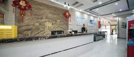 A reception area with a marble counter, a large wall mural, and a red decorative element.