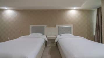 Quarto de hotel com duas camas de solteiro, uma mesa de cabeceira e cabeceira com telefone embutido.