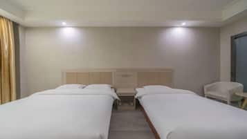 Quarto de hotel com duas camas de solteiro, cabeceira de madeira, mesa de cabeceira pequena e uma cadeira.
