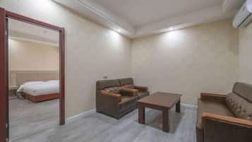 Quarto de hotel com cama, sofá, mesa de centro e espelho.