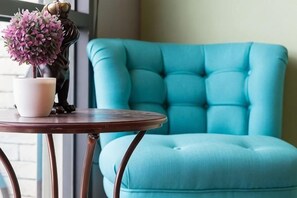 A teal upholstered chair and a round table with a white vase and a pink flower arrangement. - Angel Inn (Hualien)