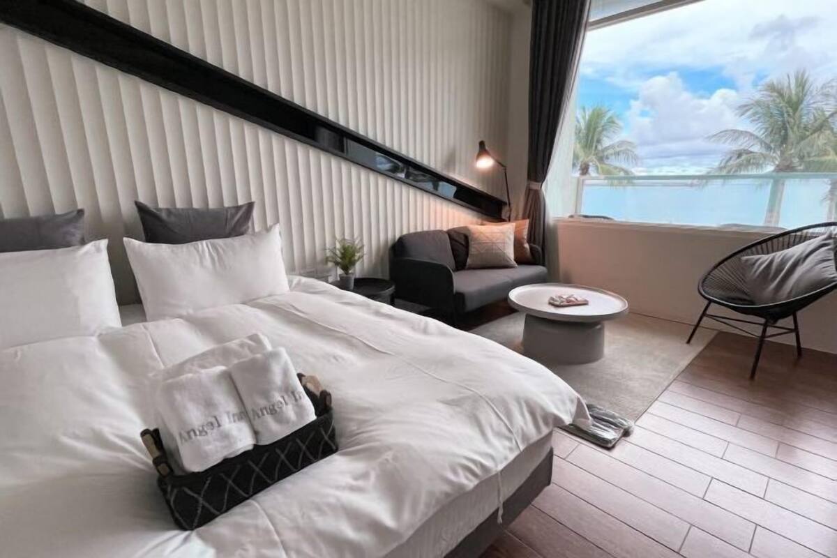 A modern hotel room with a bed, a sofa, a small table, and a chair.
