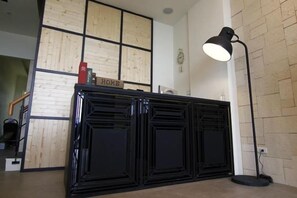 A reception desk with a 'HOME' sign, a clock on the wall, and a floor lamp. - Angel Inn (Hualien)