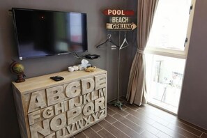 A room with a television, a wooden block letter display, and a sign indicating pool, beach, and grilling amenities. - Angel Inn (Hualien)