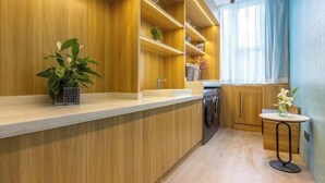 A modern kitchen with wooden cabinetry, a built-in dishwasher, and a small round table with a vase of flowers. - Homeinn · neo (Jiuquan West Street Bus Station) (Jiuquan)