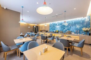 A modern restaurant interior with multiple dining tables and chairs, a bar area, and a blue-tiled backsplash. - Homeinn · neo (Jiuquan West Street Bus Station) (Jiuquan)