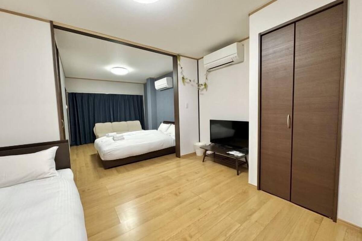 A hotel room with a bed, a TV, a wardrobe, and an air conditioning unit.