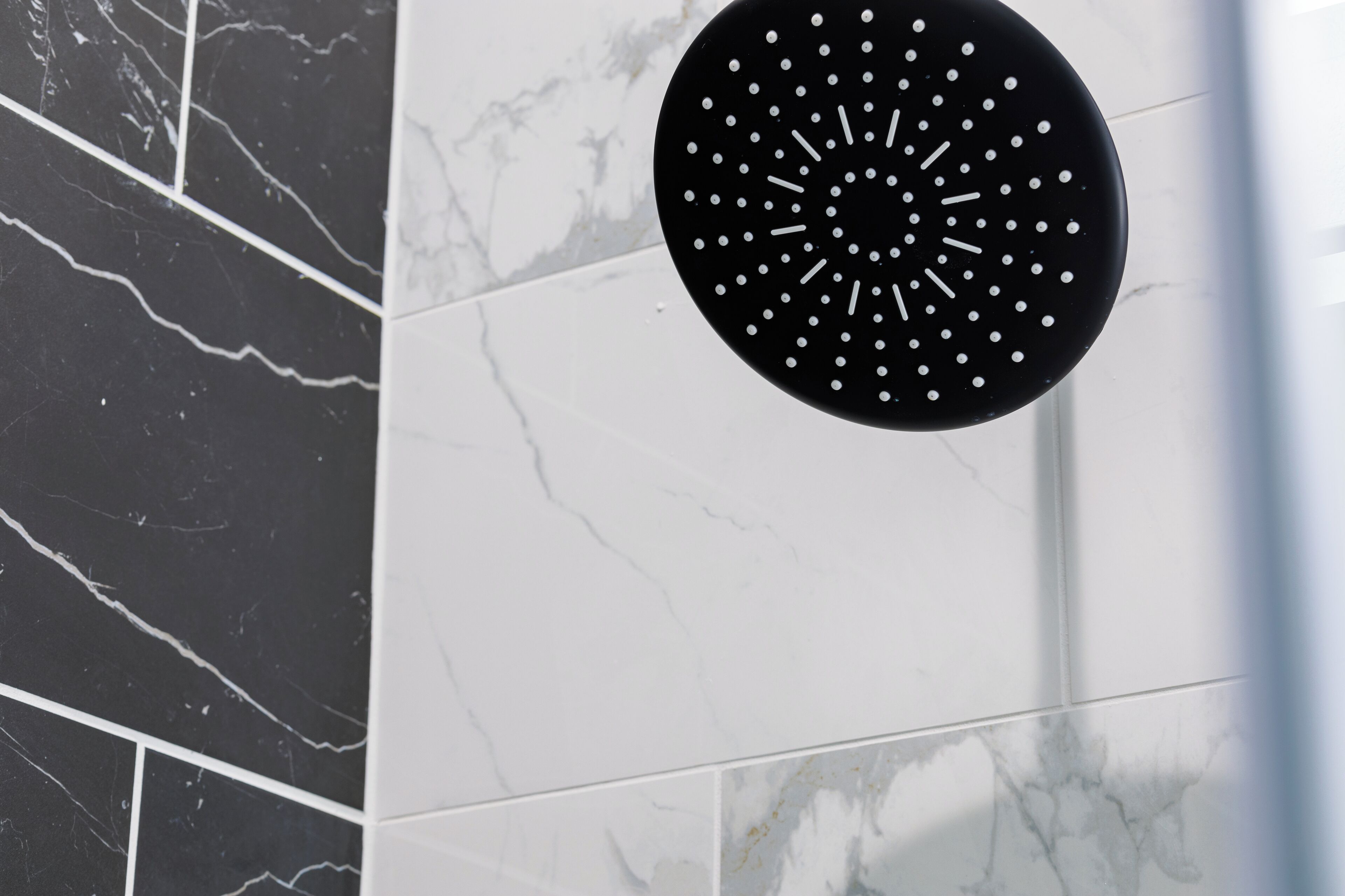 A black circular object with white dots on a tiled wall.