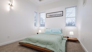 A bedroom with a single bed, two bedside tables with lamps, a framed picture on the wall, and two windows with blinds. - Modern 2Bedroom house in Dallas with WiFi (Dallas)
