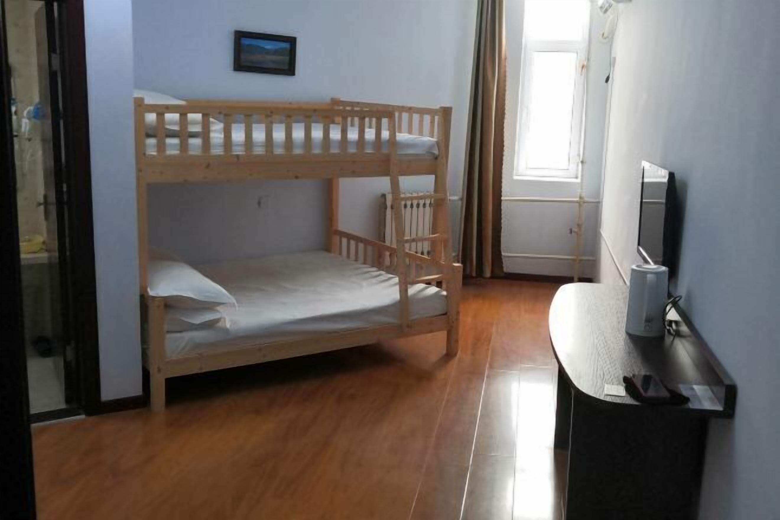 A bunk bed in a room with a window, a small table, and a mirror.