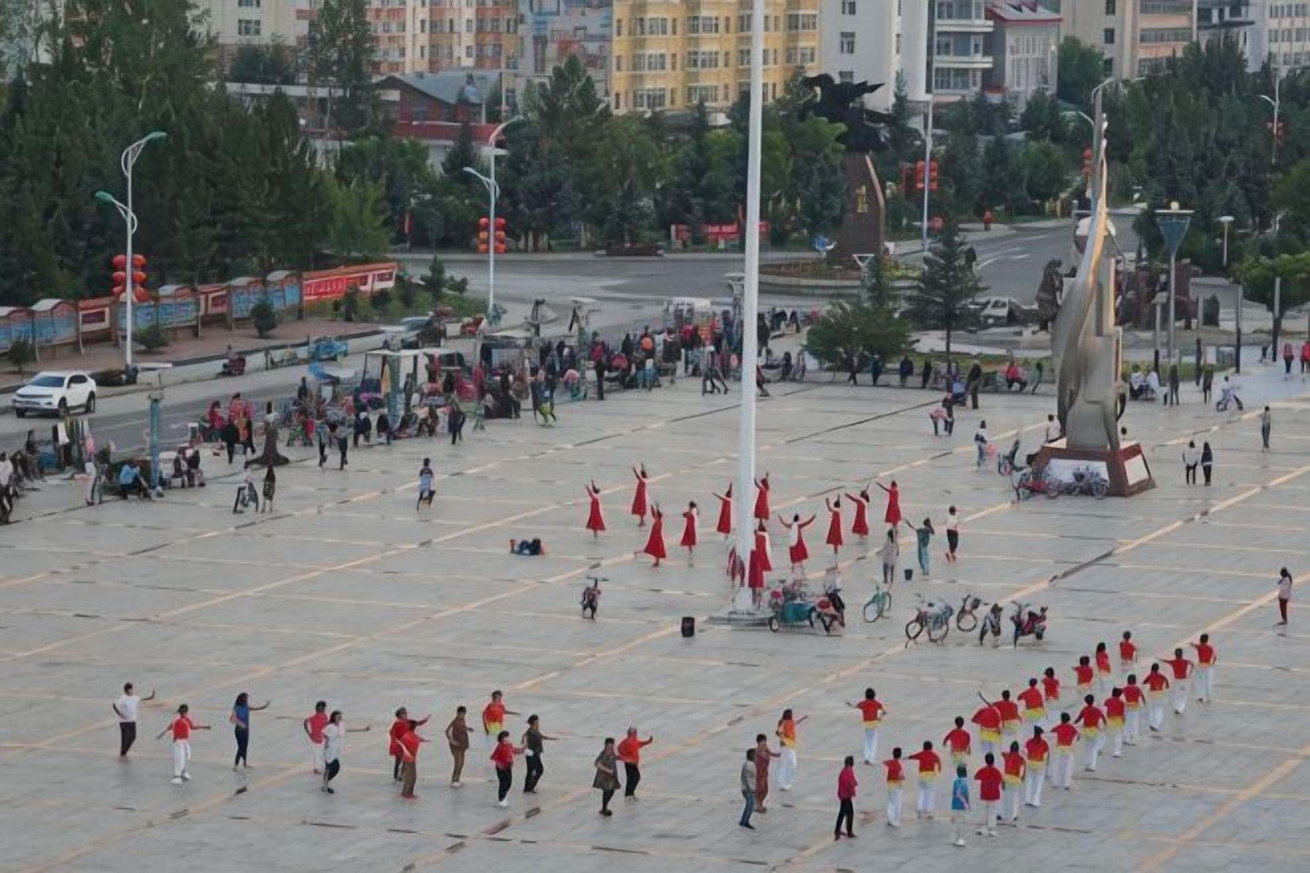 A public square with a large open space, a monument, and a crowd of people.