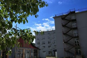 Ein mehrstöckiges Gebäude mit Feuerleiter, ein rotes Gebäude im Hintergrund und ein klarer Himmel.