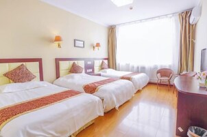 A hotel room with two beds, a desk, a chair, and a large window with curtains.
