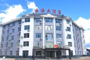 A multi-story building with a flat facade, large windows, and a sign with Chinese characters. - Moerdaoga Yunhai Hotel (Ergun)