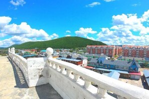 Un pont doté d’une rambarde, avec une vue sur une ville, ses bâtiments et une colline en arrière-plan.