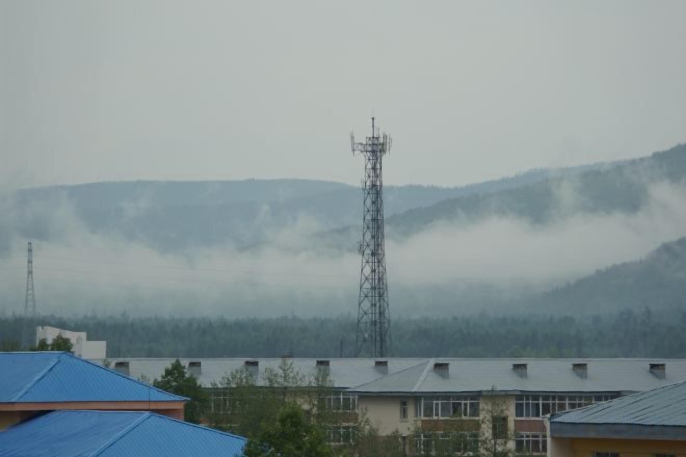 Un edificio de techo plano con una alta torre de comunicaciones al fondo.