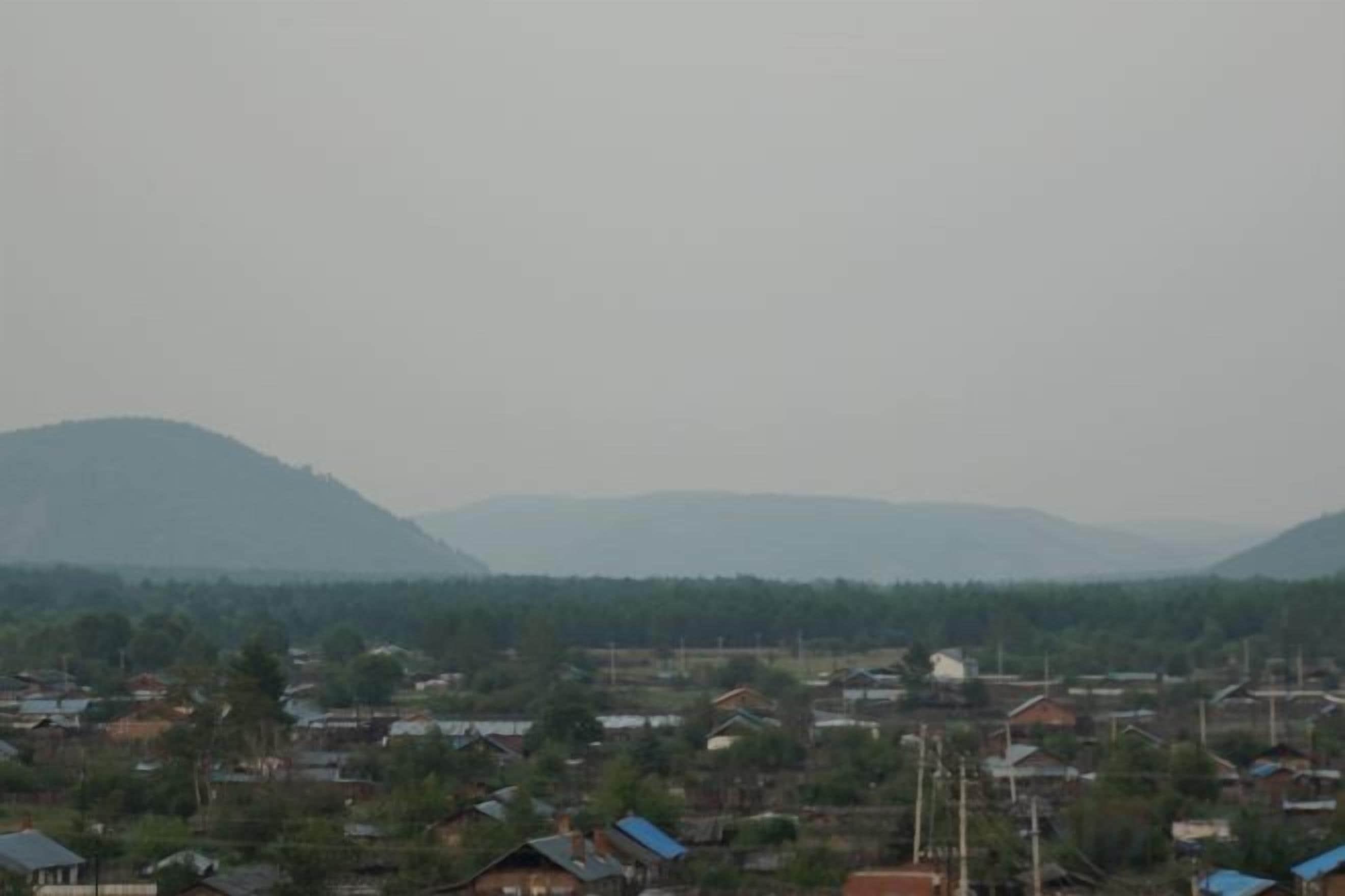 A residential area with houses and a hilly landscape in the background.