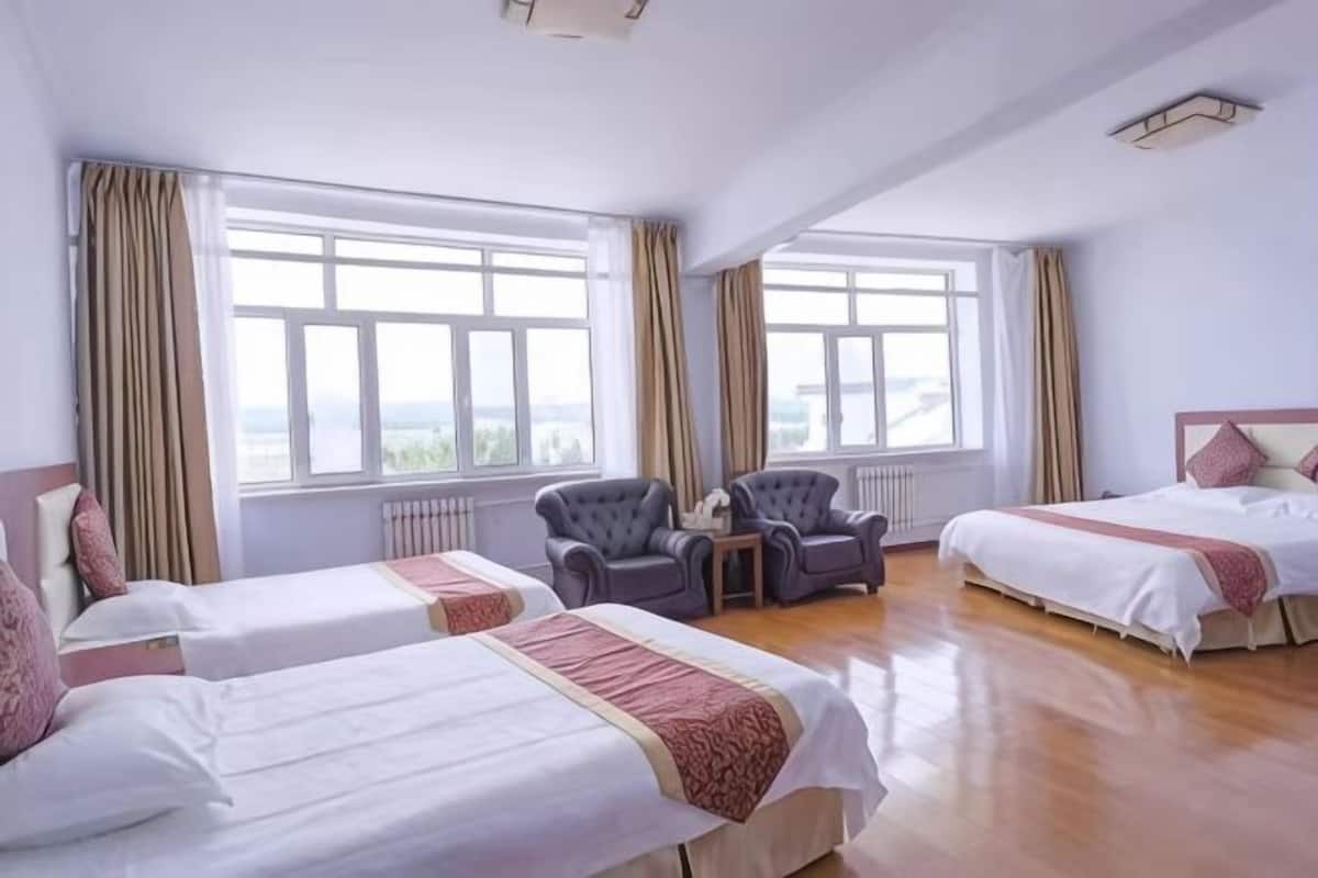 Een hotelkamer met twee bedden, een zithoek met stoelen, grote ramen en uitzicht.