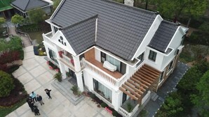 Una casa de dues plantes amb teulada gris, un balcó i una escala que puja a la planta superior.