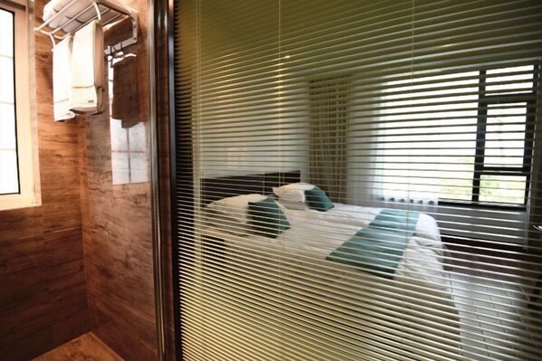 A bedroom with a bed, a window with blinds, and a towel rack. - HSL Manor Homestay (Shanghai)