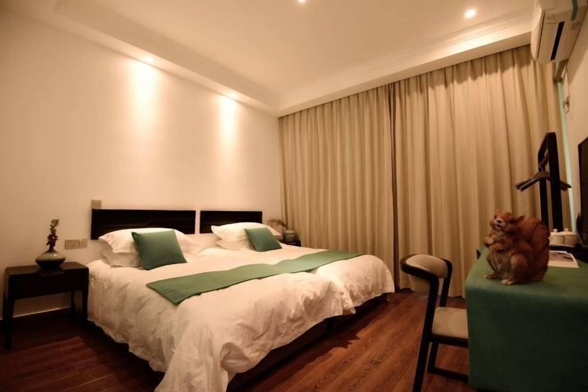 Une chambre d’hôtel avec un lit, une chaise, une petite table et un rideau.