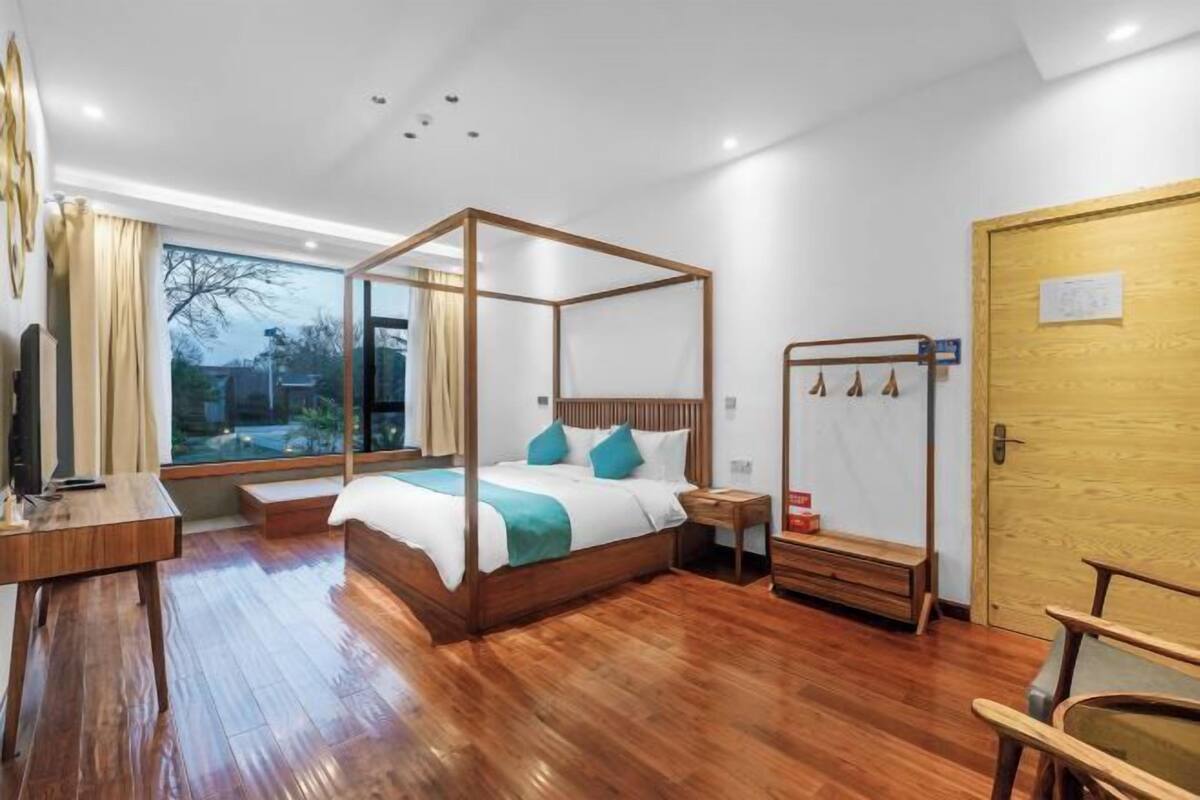 Une chambre moderne avec un lit à baldaquin, un plancher en bois, un bureau et une grande fenêtre.