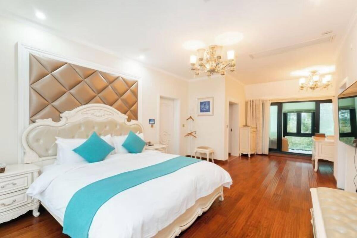Une chambre à coucher avec un grand lit, un lustre et une vue sur l’extérieur.