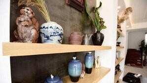 Una estanteria amb objectes decoratius, com ara testos de ceràmica, una figura d'animal de ceràmica i un vas amb plantes seques.