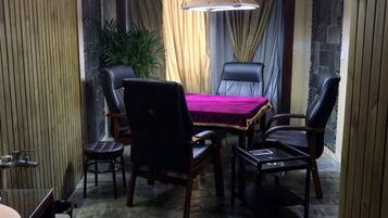 A dining area with a table and four chairs, a hanging light fixture, and a potted plant.