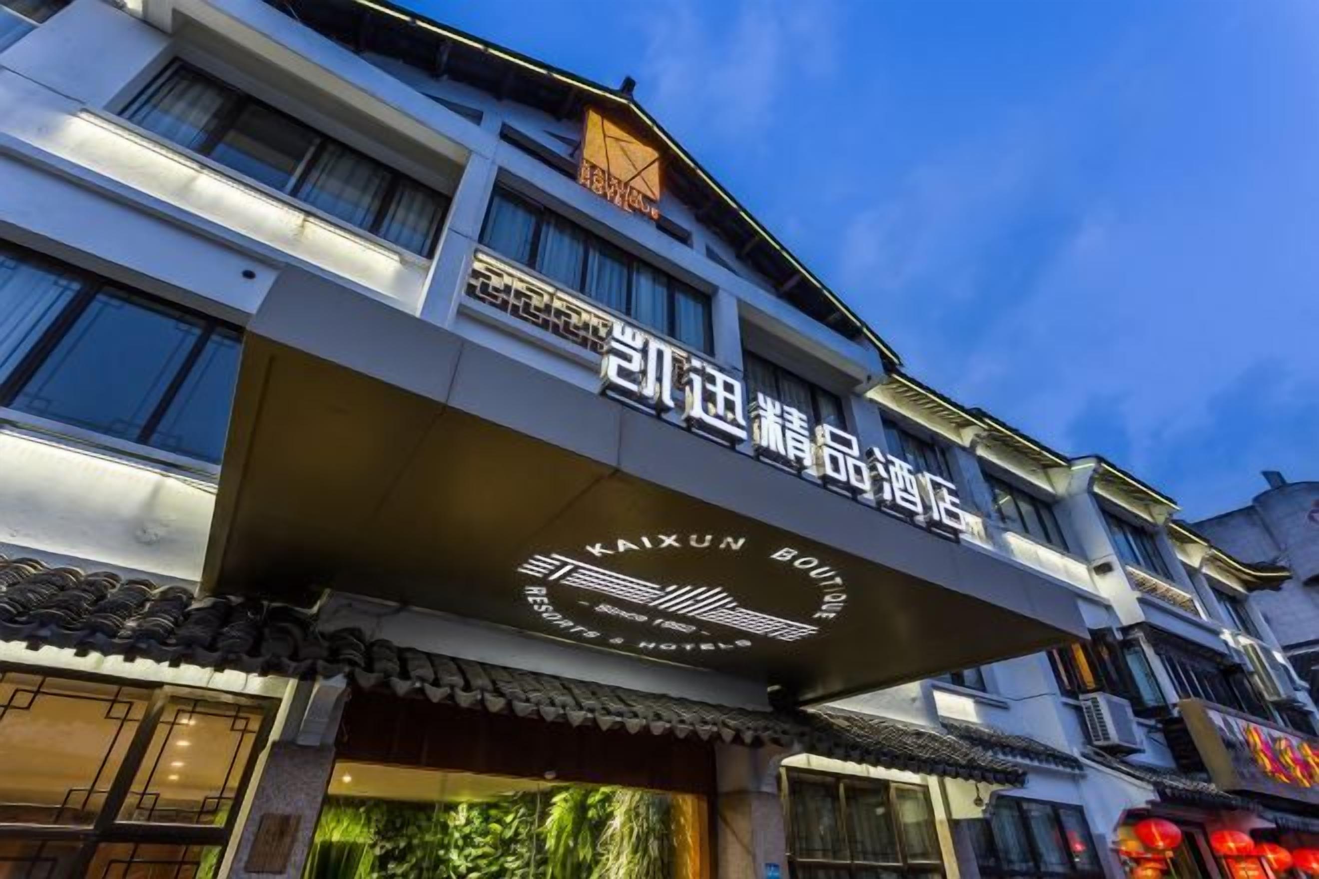 A hotel with a traditional architectural style, featuring a prominent sign with Chinese characters and a logo.