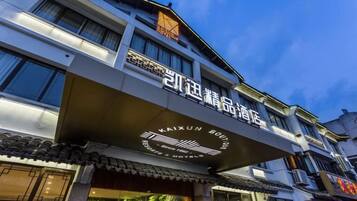 A hotel with a traditional architectural style, featuring a prominent sign with Chinese characters and a logo.