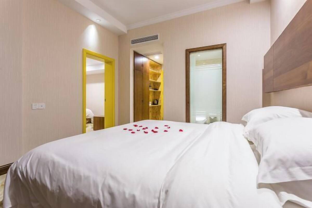A hotel room with a large bed, a mirror, and a wardrobe.