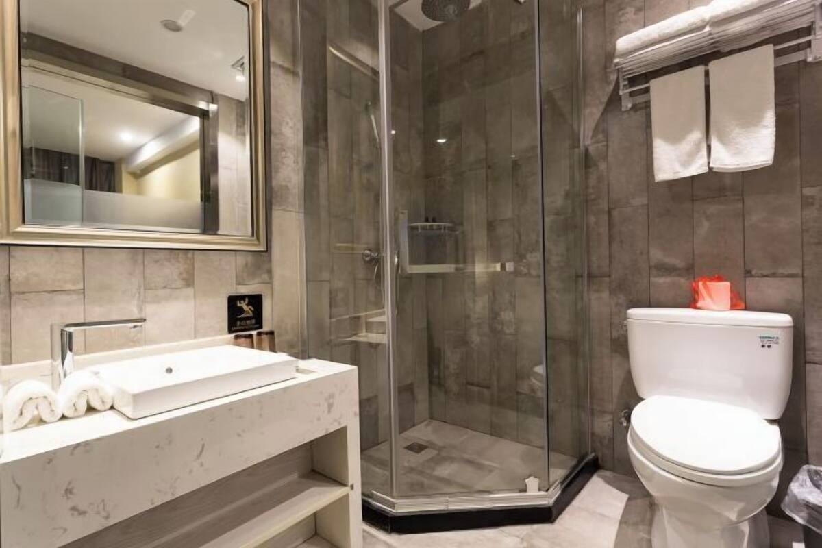 A modern bathroom with a glass-enclosed shower, a white sink, and a toilet.