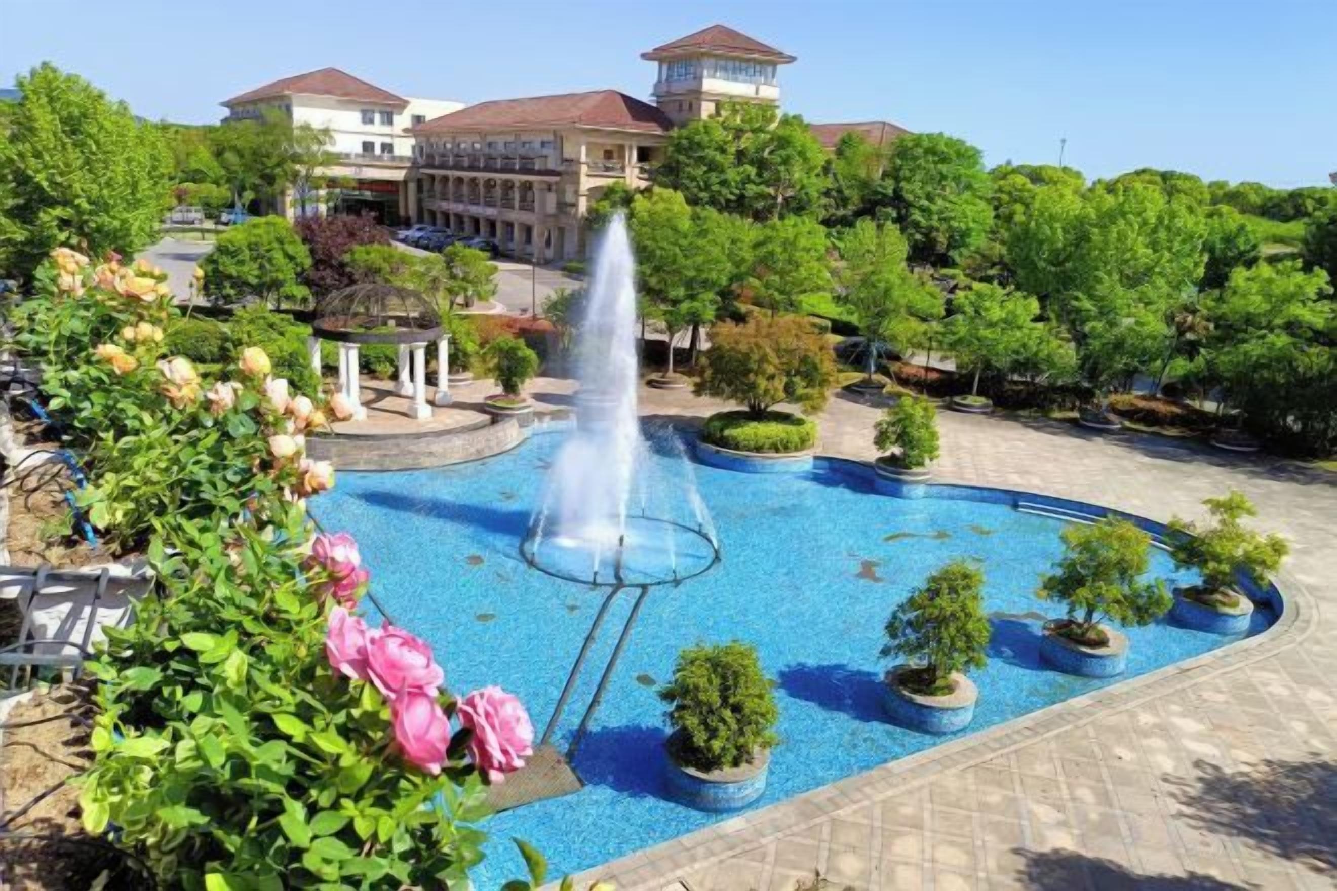 A courtyard with a fountain, potted plants, and a gazebo.