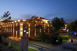 A hotel with a long facade, multiple windows, and a well-lit entrance.