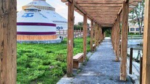 A traditional yurt with a blue and red design, surrounded by a wooden pergola and a stone pathway. - Guli Hotel (Nanjing)