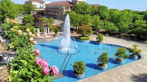A courtyard with a fountain, potted plants, and a gazebo. - Guli Hotel (Nanjing)