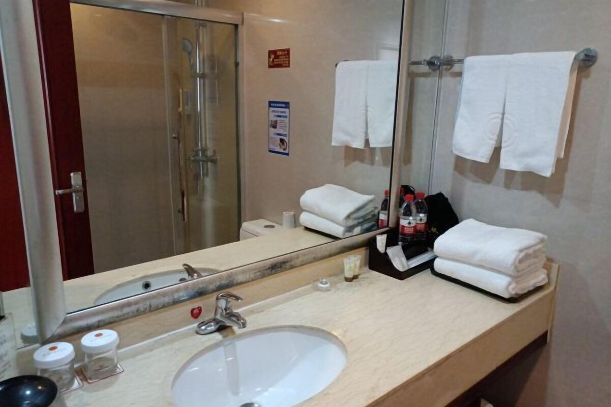 A bathroom with a sink, mirror, towel rack, and a shower visible through the glass door.