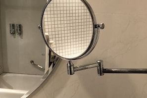 A bathroom with a mirror, a towel rack, and a shower area. - Golden Eagle Hotel (Zhoushan)