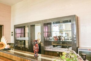 Un espace d’accueil d’hôtel avec un comptoir en marbre, un vase décoratif et une vitrine en verre contenant divers objets.