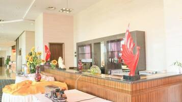 A hotel reception area with a reception desk, a seating area, and a large window.