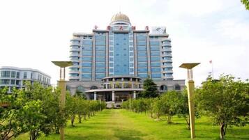 A large hotel with a central dome and multiple floors, surrounded by a well-maintained lawn and trees.