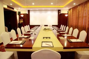 A conference room with a long table, chairs, and a projector screen. - Golden Eagle Hotel (Zhoushan)