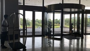 A revolving door with a view of a parking lot and greenery outside. - Golden Eagle Hotel (Zhoushan)