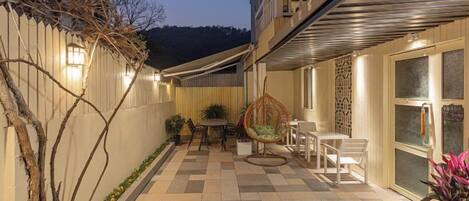 A patio area with a checkered floor, outdoor seating, and a hanging chair.
